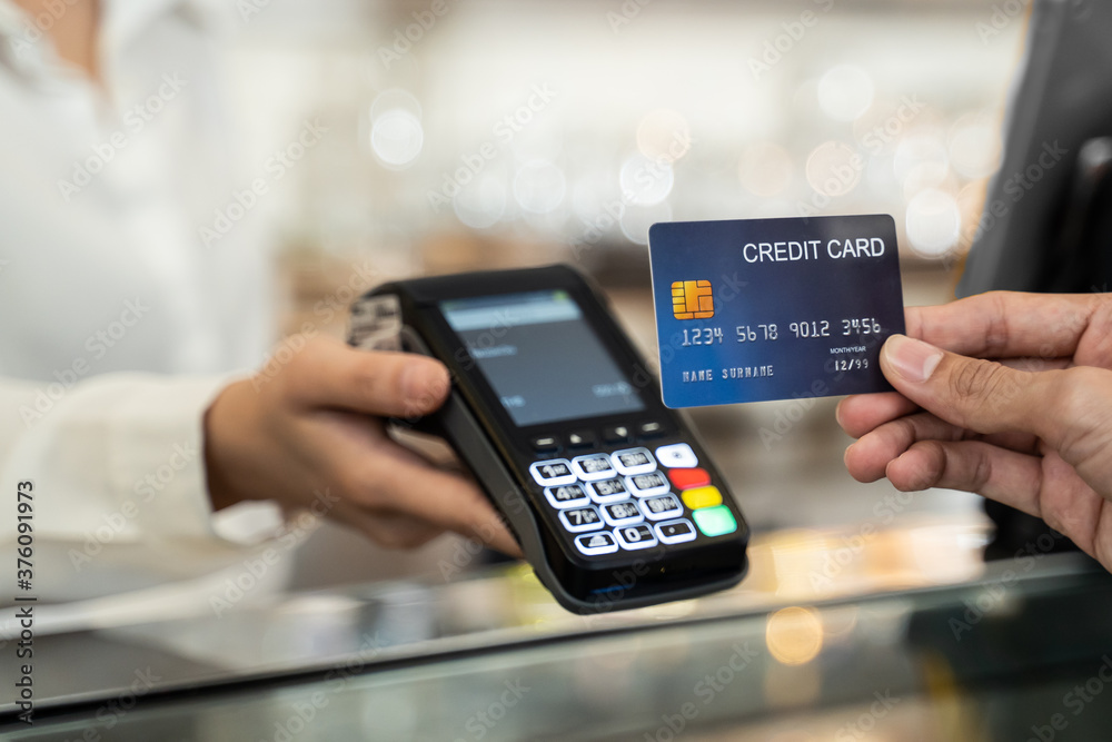 Customer using credit card for payment at cashier in cafe restaurant.